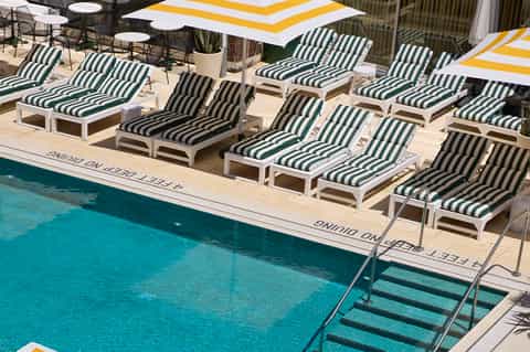 Indoor pool deck with green and white striped lounge chairs and yellow umbrellas
