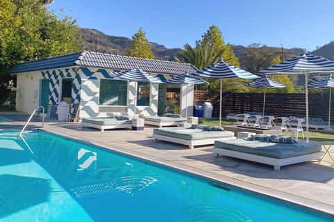 Contemporary pool house with geometric patterns, striped umbrellas, and mountain backdrop