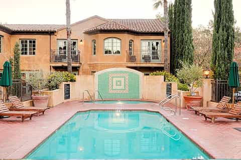 Resort pool courtyard with turquoise water, terra cotta Spanish colonial architecture, lounge chairs