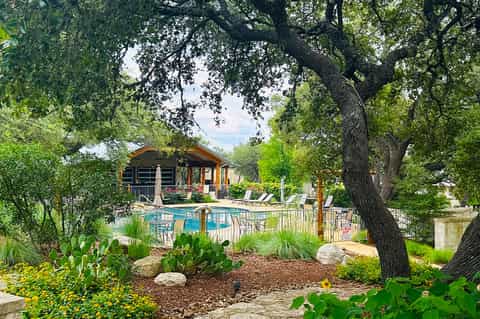 Resort pool nestled among large oak trees with yellow cabana and lawn seating