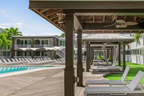Modern resort pool deck with lounge chairs, umbrellas, multi-story residential buildings