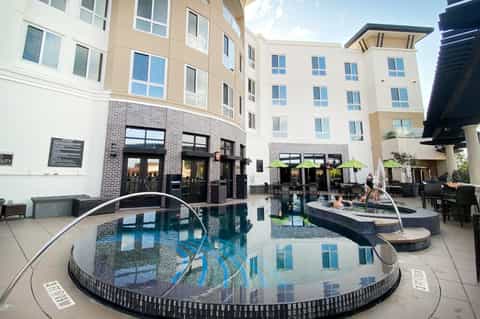 Urban hotel courtyard with circular hot tubs, modern architecture, and glass entrance doors