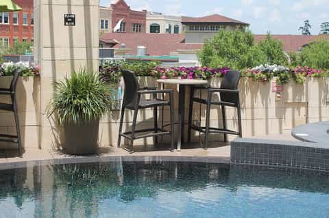 Rooftop bar seating with flowering planters overlooking historic brick buildings