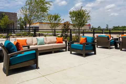 Modern resort lounge area with colorful pillows and wicker seating on patio overlooking fields