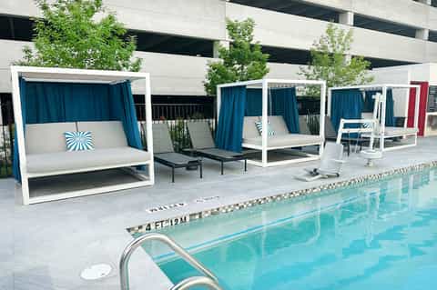 Contemporary pool deck with cabanas, white pergolas, blue curtains, and lap pool