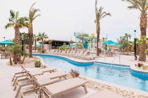 Resort lazy river with palm trees, water slides, and lounge chairs