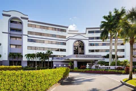 DoubleTree Hilton hotel exterior with white art deco architecture, palm trees, and welcome signage
