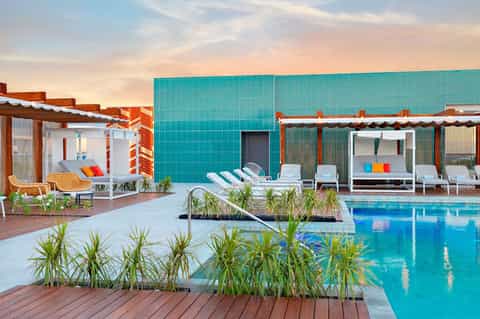 Modern resort pool with turquoise water, cabanas, and architectural canopies