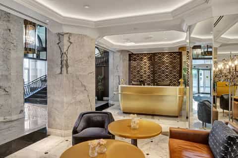 Modern luxury hotel lobby with marble walls, golden reception desk, and contemporary furnishings