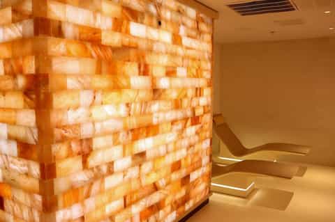Modern spa interior with glowing Himalayan salt brick wall and curved seating benches