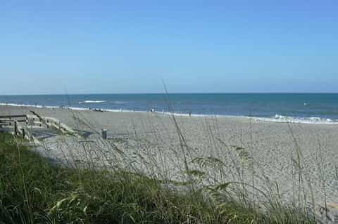 Sandy beach with beach grass, ocean waves, and clear blue sky overlooking the Atlantic