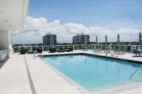 Rooftop pool overlooking city with residential towers, clear railings, and contemporary furnishings