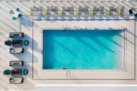Aerial view of rectangular pool with lounge chairs and shadows on deck