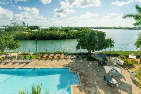 Waterfront resort pool with mangrove views, loungers, and boat dock access