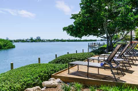 Waterfront lounge chairs on wooden deck overlooking bay with mangrove trees