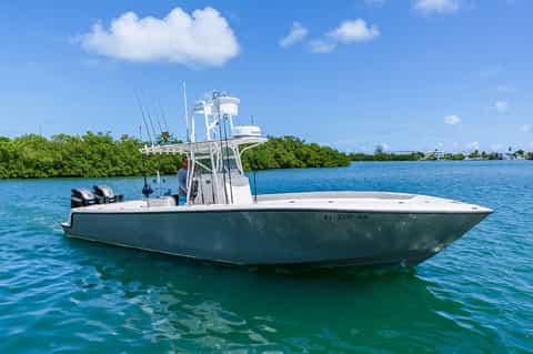 Green and white sport fishing boat moored in turquoise tropical waters with mangroves
