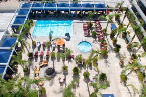 Aerial view of resort pool complex with red lounge chairs, umbrellas, and tropical landscaping