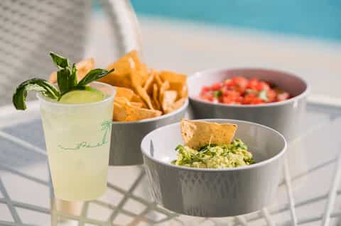 Poolside dining with margarita cocktail, chips, guacamole, and salsa bowls