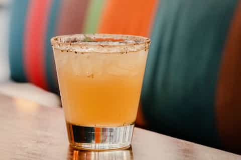 Cocktail with salt-rimmed glass and colorful striped background on wooden counter