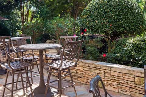 Outdoor terrace seating area surrounded by lush greenery and flowering plants