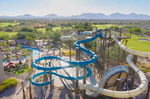 Aerial view of resort water park with blue slides and valley landscape
