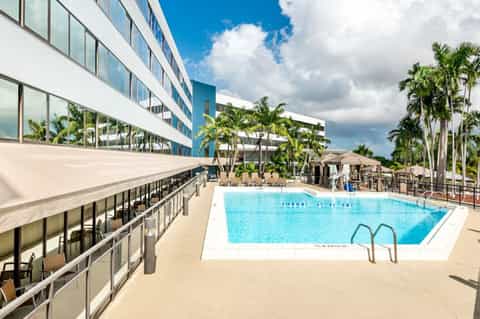 Modern hotel pool deck with contemporary building and palm trees