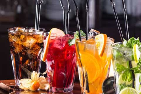 Assorted colorful cocktails with citrus garnishes and fresh mint leaves