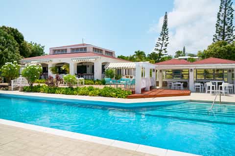 Resort pool facility with white main building, turquoise water, and tropical vegetation