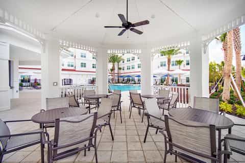 Covered poolside pavilion with lounge chairs, high ceiling, fan, and views of resort pool and palm trees