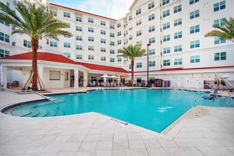 Resort courtyard pool with red-roofed hotel building and palm trees