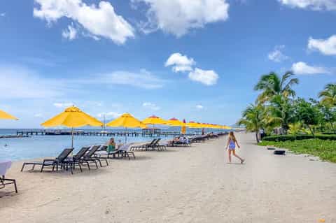 Beach club with yellow umbrellas, lounge chairs, pier, and palm trees