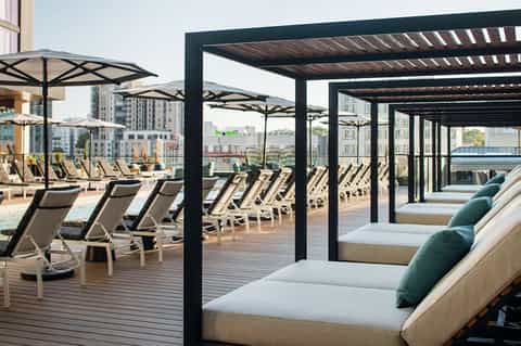 Upscale rooftop terrace with modern lounge chairs, umbrellas, and city skyline views