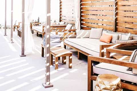 Minimalist spa area with wooden sun loungers and neutral cushions separated by wooden privacy screens