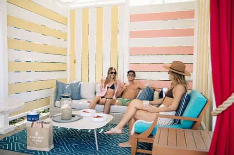 Guests relaxing on lounge seating in bright cabana with striped outdoor walls