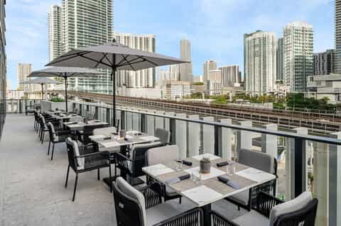 Rooftop dining terrace with city skyline views, umbrellas, and contemporary furniture