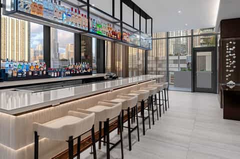 Upscale rooftop bar with city skyline views, white leather seating, and premium liquor display