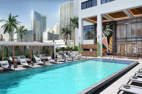 Modern rooftop pool with turquoise water, sun loungers, wooden pergolas, and city skyline views