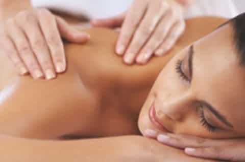 Woman receiving relaxing spa massage treatment on massage table with therapist's hands
