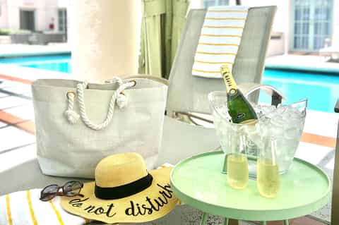 Poolside table with champagne, hat, sunglasses, and beach bag at resort