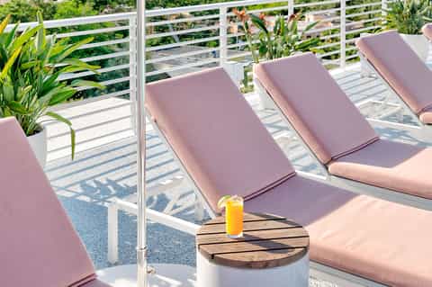 Oceanview deck with pink lounge chairs, white railings, and tropical plants