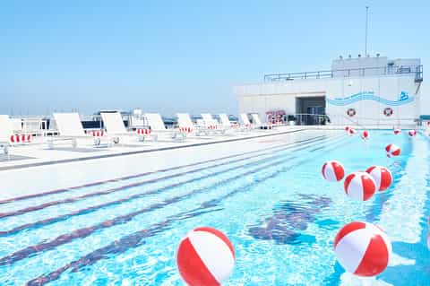 Resort rooftop pool with lane markings, beach balls, loungers, and ocean skyline