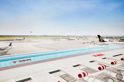 Aircraft wing and tail at airport with runway and aircraft in background during daylight