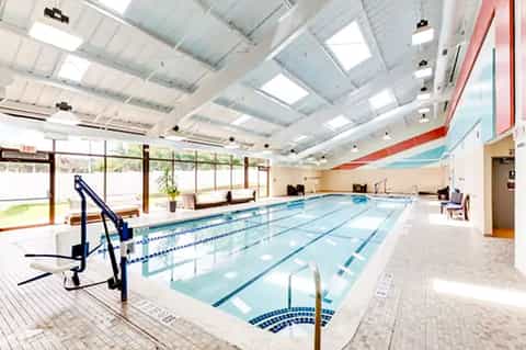 Indoor lap pool with lane markers in bright, naturally-lit facility with skylights and large windows