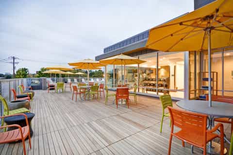 Contemporary hotel terrace with yellow umbrellas, modern furniture, and glass building