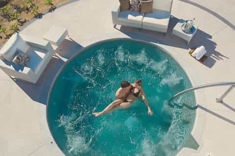 Aerial view of two people swimming in a circular turquoise pool