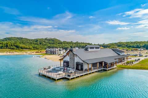 Modern waterfront lodge with dark roof, wooden accents, deck, and turquoise lake views