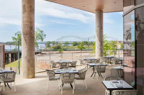 Waterfront restaurant patio with river bridge view and modern furnishings