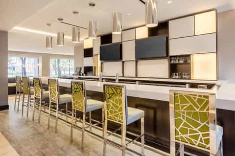 Modern hotel bar with lime green patterned chairs and contemporary light fixtures