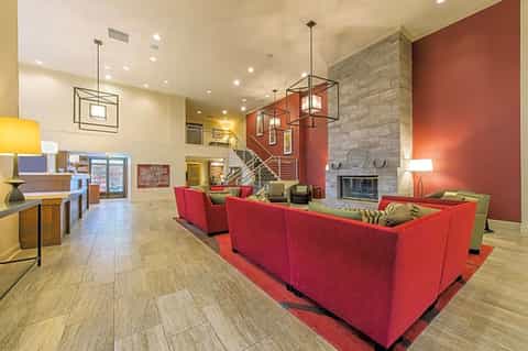 Hotel lobby interior with red seating, fireplace, modern lighting, and two-story design