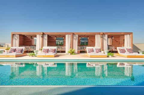 Luxury cabanas with wooden structures beside a bright turquoise swimming pool